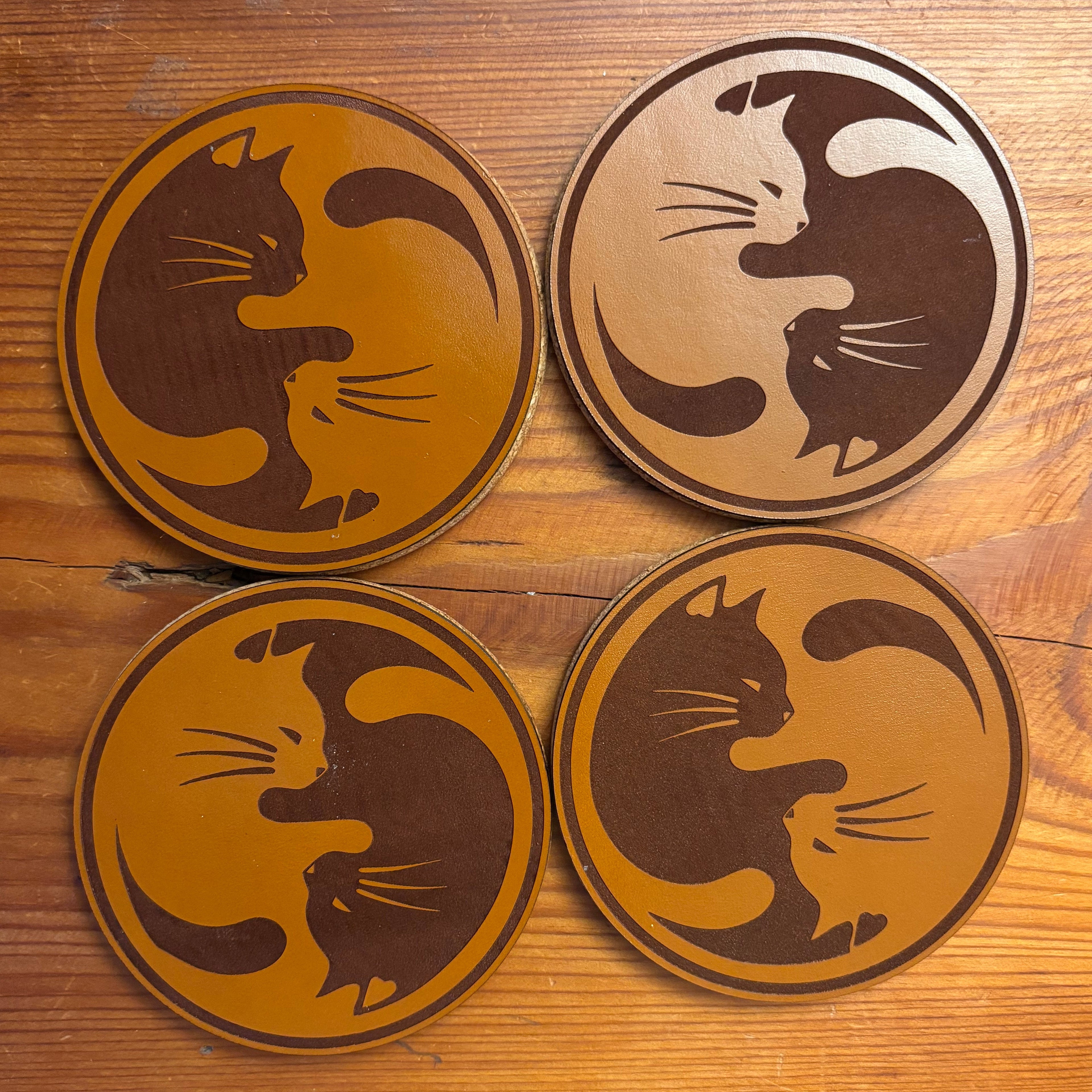 Four wooden coasters with cat designs on a wooden surface