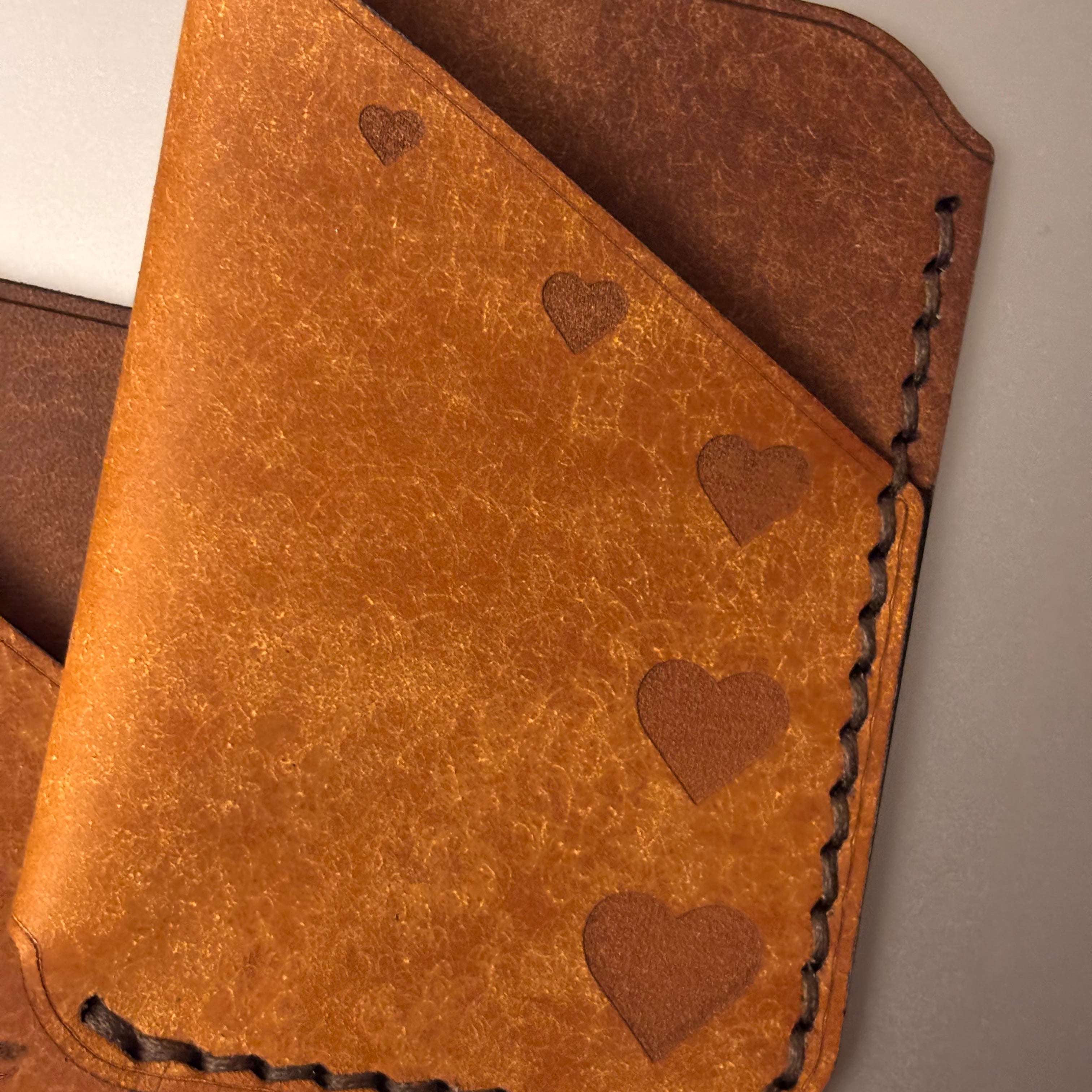 Brown leather wallet with heart patterns on a neutral background