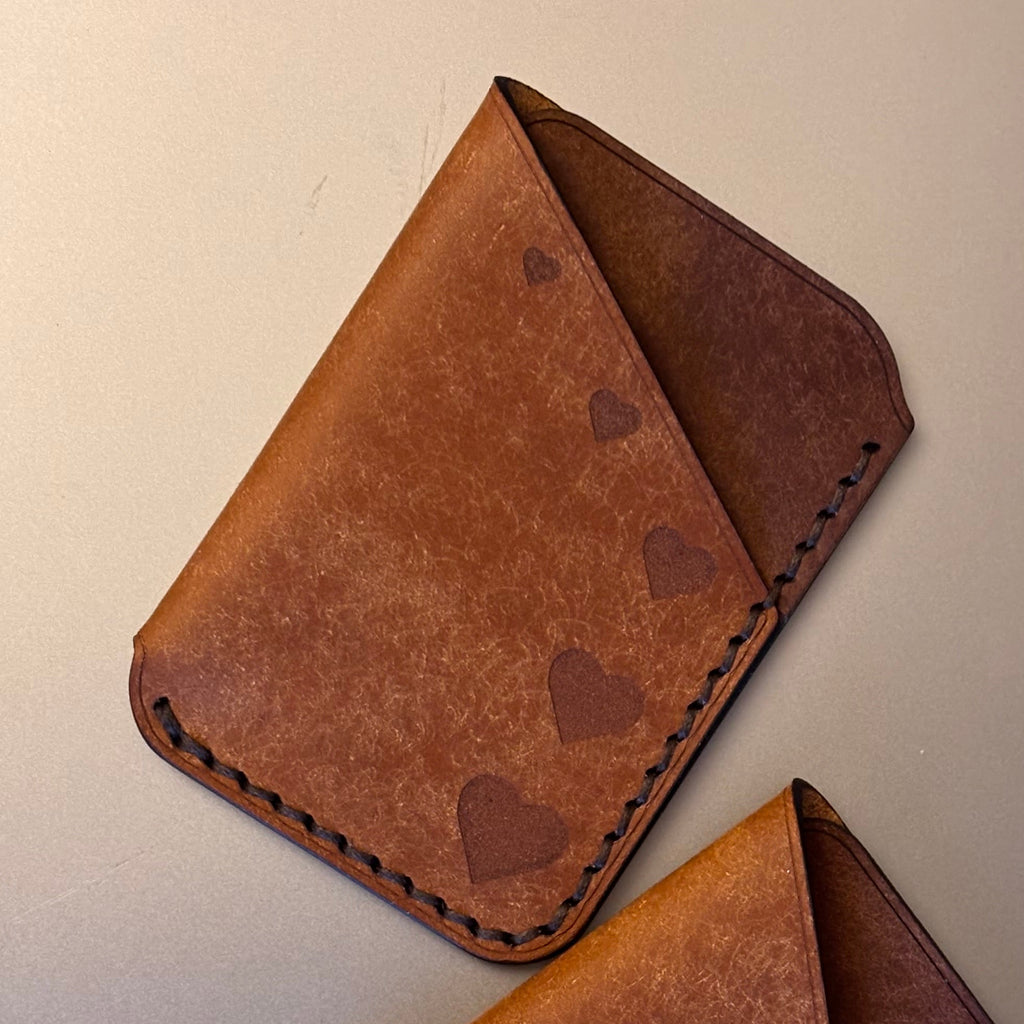 Two brown leather card holders on a light gray surface