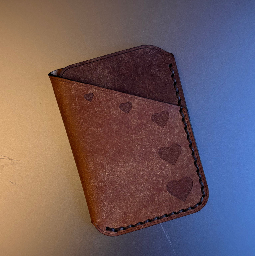 Brown leather wallet with heart patterns on a blue and yellow gradient background